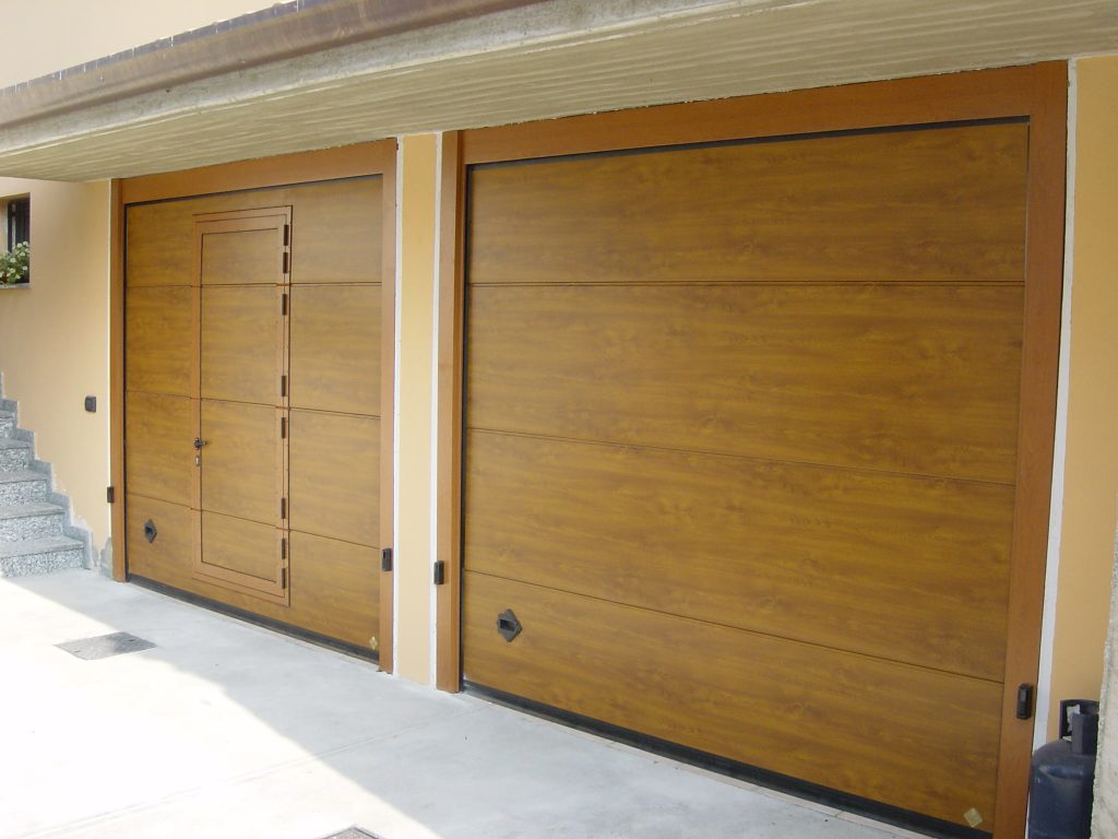 Doppia porta per garage sezionale simil legno con porta pedonale per ingresso a piedi facilitato